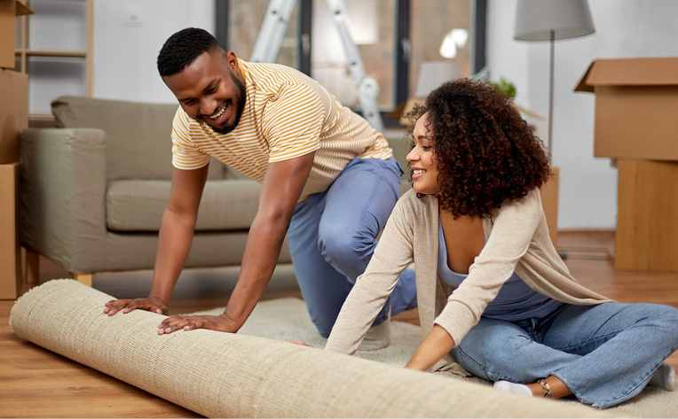 couple unrolling new rug in living room with brand new flooring